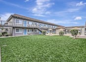 Thumbnail 30 of 30 - the backyard of a condo building with green grass and a lawn