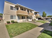Thumbnail 6 of 33 - A beige apartment building with a green lawn in front.
