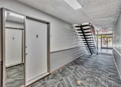 Thumbnail 23 of 41 - A hallway with a staircase on the right and a door on the left.