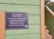 Thumbnail 14 of 14 - A sign on a building that reads "154 Madison Apartments" and provides contact information for assistance.