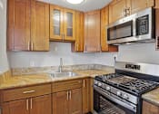 Thumbnail 8 of 17 - A kitchen with a stove, sink, and cabinets.