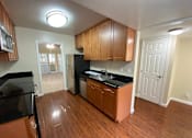 Thumbnail 22 of 23 - A kitchen with wooden cabinets and black countertops.