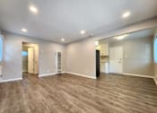 Thumbnail 29 of 50 - A spacious room with wooden flooring and white walls.