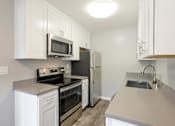 Thumbnail 6 of 27 - A kitchen with white cabinets and stainless steel appliances.