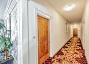 Thumbnail 17 of 42 - A long hallway with a red carpet and white walls.