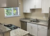 Thumbnail 26 of 43 - A kitchen with granite countertops and white cabinets.