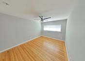 Thumbnail 17 of 47 - A room with a ceiling fan and wooden flooring.