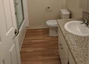 Thumbnail 41 of 42 - A white bathroom with wood floors and a window.