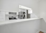 Thumbnail 91 of 92 - A white kitchen with a stove and a sink.