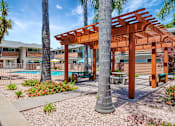 Thumbnail 4 of 25 - A wooden pergola is in the middle of a garden with a pool in the background.