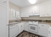 Thumbnail 50 of 51 - A white kitchen with a sink, stove, and oven.