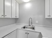 Thumbnail 37 of 40 - A kitchen with white cabinets and a sink.
