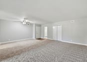 Thumbnail 8 of 33 - A spacious room with a ceiling fan and carpeted floor.