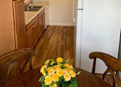 Thumbnail 29 of 32 - a kitchen with a refrigerator and a table with flowers