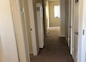 Thumbnail 11 of 22 - A long hallway with white doors on both sides.