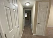Thumbnail 19 of 23 - A hallway with white doors and carpeted floor.