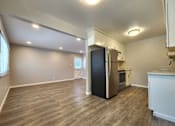 Thumbnail 27 of 50 - A kitchen with a black fridge and wooden floors.