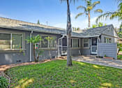 Thumbnail 5 of 31 - A building with a grey exterior and a palm tree in front.