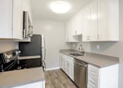Thumbnail 9 of 27 - A kitchen with white cabinets and stainless steel appliances.