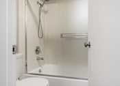 Thumbnail 29 of 32 - A white toilet is next to a shower in a bathroom.