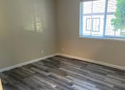 Thumbnail 27 of 43 - A room with a window and wooden flooring.