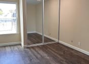 Thumbnail 26 of 36 - an empty living room with wood floors and a mirrored closet