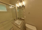 Thumbnail 46 of 47 - A bathroom with a sink, toilet, and mirror.