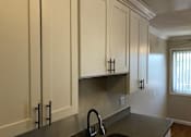 Thumbnail 30 of 62 - a kitchen with white cabinets and a sink