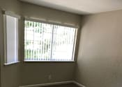 Thumbnail 18 of 26 - A room with a carpeted floor and a window with blinds.