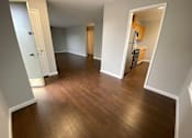 Thumbnail 32 of 41 - a living room and hallway with wood floors and a kitchen