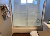 Thumbnail 32 of 43 - A white toilet sits in a bathroom with a glass shower door.