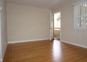 Thumbnail 18 of 22 - A room with wooden floors and a door leading to a balcony.