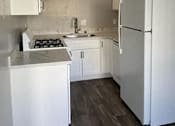 Thumbnail 28 of 33 - A white kitchen with a refrigerator, sink, and stove.