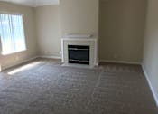 Thumbnail 13 of 26 - A living room with a fireplace and a carpeted floor.