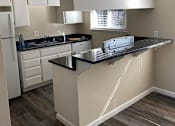 Thumbnail 23 of 43 - A kitchen with a black counter top and white cabinets.