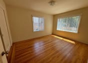 Thumbnail 1 of 19 - an empty living room with wood floors and two windows