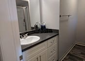Thumbnail 26 of 63 - A bathroom with a sink, mirror, and wooden floors.