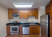 Thumbnail 15 of 23 - an empty kitchen with wooden cabinets and stainless steel appliances