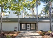 Thumbnail 3 of 23 - the entrance to a white building with a sidewalk and trees