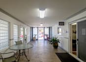 Thumbnail 9 of 23 - a dining room with a glass table and chairs and a hallway with doors and windows