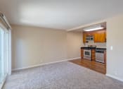 Thumbnail 16 of 23 - an empty living room and kitchen with wood cabinets and white carpet
