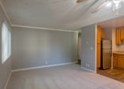 Thumbnail 18 of 23 - an empty living room with a refrigerator and a kitchen