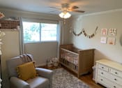 Thumbnail 22 of 32 - a nursery with a baby crib and a ceiling fan