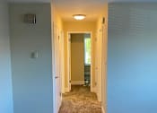 Thumbnail 32 of 43 - A hallway with a carpeted floor and white walls.