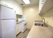 Thumbnail 11 of 20 - A kitchen with a white refrigerator, stove, and sink.