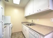 Thumbnail 12 of 20 - A kitchen with a white refrigerator, a white stove, a white dishwasher, and white cabinets.