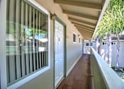 Thumbnail 10 of 20 - A long hallway with a white door and a window with blinds.