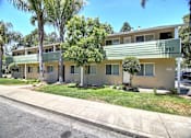Thumbnail 1 of 20 - A row of houses with green lawns and trees.