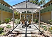 Thumbnail 3 of 20 - A patio with a table and chairs under a white roof.