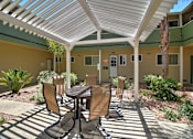 Thumbnail 5 of 20 - A patio with a table and chairs is covered by a white roof.
